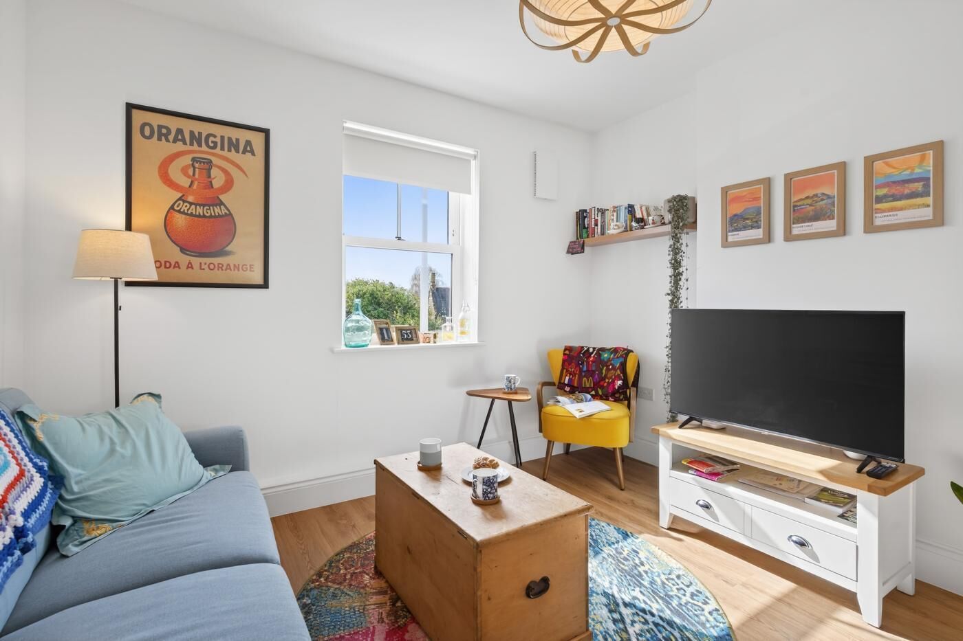 A modern living room with a sofa, coffee table, TV stand, and artwork.