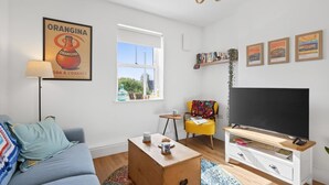 Ein modernes Wohnzimmer mit Sofa, Couchtisch, Fernseher und Kunstwerken.
