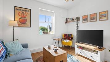 A modern living room with a sofa, coffee table, TV stand, and artwork.