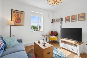 Una sala moderna con sofá, mesa de centro, mueble para televisión y obras de arte.