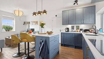 A modern kitchen with a central island, bar stools, and a dining area with a view.