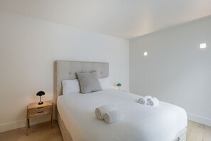 Ein Schlafzimmer mit einem Bett, einem Nachttisch, einer Lampe und gerollten Handtüchern.