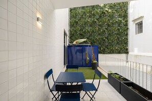 Eine Terrasse mit Tisch und Stühlen, ein blauer Zaun und eine grüne Wand mit Pflanzen.