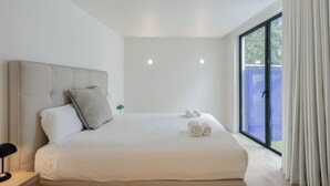 Een moderne slaapkamer met een groot bed, een nachtkastje en uitzicht door een schuifdeur.
