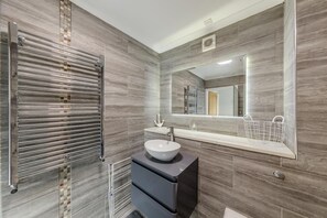 A modern bathroom with a large mirror, a vessel sink, and a towel rack.