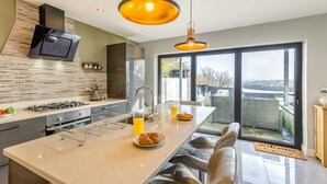 A modern kitchen with a central island, stainless steel appliances, and a large window offering a view.