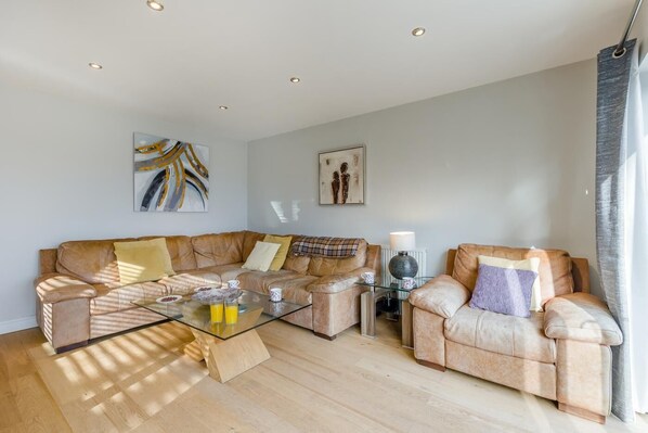 A living room with a brown leather sofa, a glass coffee table, and a lamp.