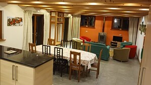 A dining area with a table and chairs, a sofa, a television, and a fireplace.