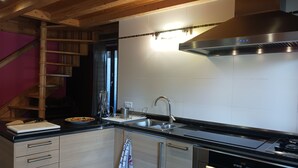 A modern kitchen with wooden beams, stainless steel appliances, and a built-in oven.