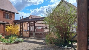 A residential area with a gravel driveway, a wooden fence, and a building with a tiled roof.