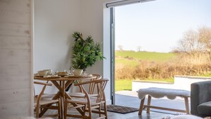 Un espace repas comprenant une table, des chaises, une plante en pot et une vue sur l’extérieur.