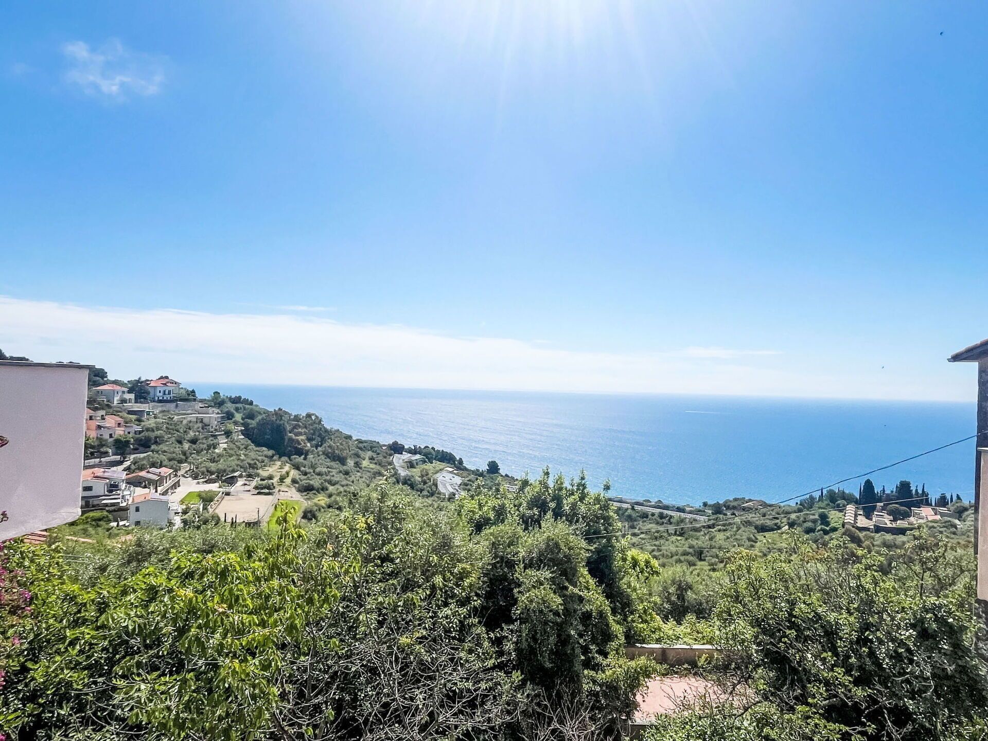 Vista costeira com casas, vegetação e o mar.