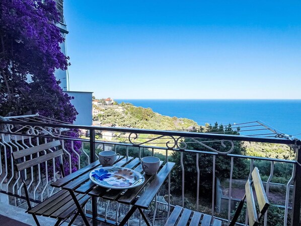 Un balcon avec une table, des chaises et une vue sur la mer.