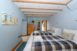 A bedroom with two beds, a wooden dresser, a painting, and a mirror. - 5 Bed in Tuckenhay (oc-o35004) (Tuckenhay)