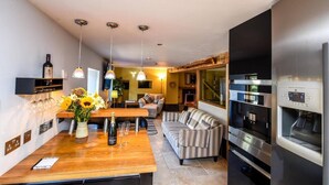 Una cucina moderna con piano in legno, una bottiglia di vino e bicchieri, un divano a righe e un forno a incasso.