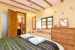 A bedroom with a bed, wooden dresser, a window with a view, and a bathroom with a shower and toilet. - 5 Bed in Tuckenhay (oc-o35004) (Tuckenhay)