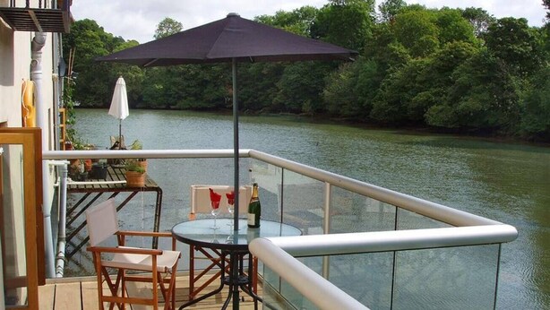 Un balcone con tavolo, sedie e ombrellone.