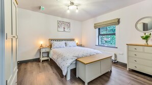 Ein Schlafzimmer mit Bett, Nachttischen, einem Fenster mit Blick, einem Deckenventilator und einer Heizung.