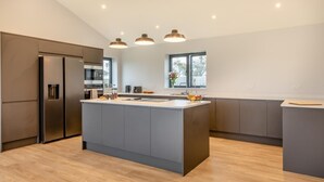 A modern kitchen with a central island, built-in appliances, pendant lighting, and a large window. - 3 Bed in West Pennard (oc-b34974) (Coxbridge)