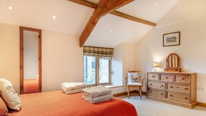 Ein Schlafzimmer mit Bett, Kommode, Stuhl, Fenster und Spiegel.