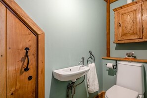 A bathroom with a wooden door, a white sink, a toilet, and a wooden cabinet above the sink. - 5 Bed in Branthwaite (oc-r35029) (Branthwaite)