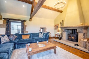 A cozy living room with a stone fireplace, a blue sofa, and a wooden coffee table. - 5 Bed in Branthwaite (oc-r35029) (Branthwaite)