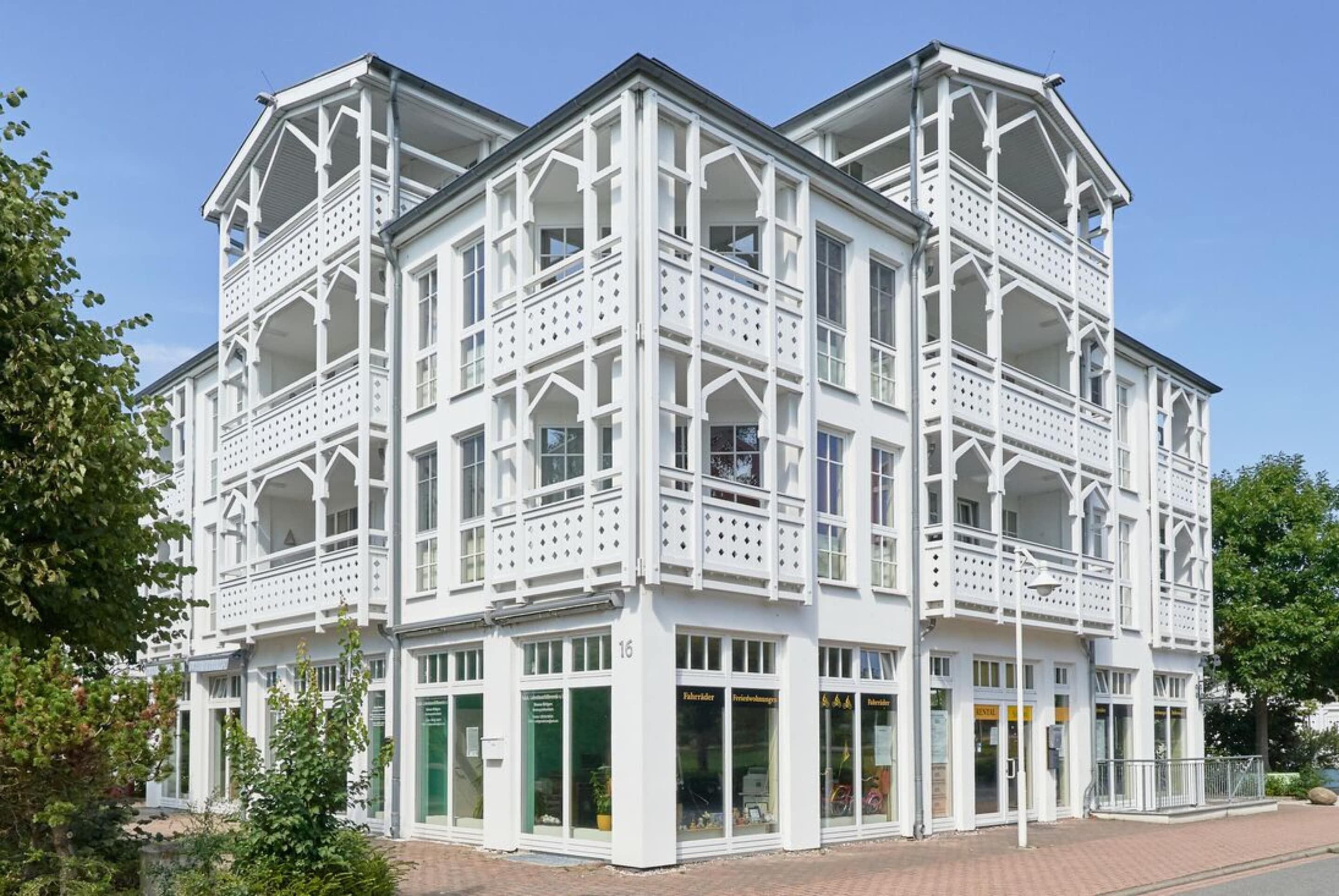 Un bâtiment blanc doté de nombreux balcons et de grandes fenêtres, qui ressemble probablement à un hôtel ou à un bâtiment public.