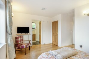 A bedroom with a bed, a chair, a television, and a door leading to a bathroom. - 3 Bed in Polruan (oc-l35010) (Fowey)