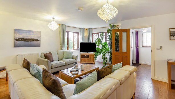 A living room with a sofa set, a television, a coffee table, and a large plant. - 3 Bed in Polruan (oc-l35010) (Fowey)