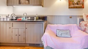 A bedroom with a bed, a nightstand, a wall-mounted lamp, and a painting above the bed.