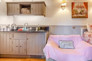 Une chambre à coucher avec un lit, une table de chevet, une lampe fixée au mur et un tableau au-dessus du lit.