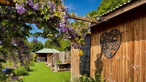A wooden building with a heart-shaped metal decoration, a well-maintained lawn, and a wooden fence.