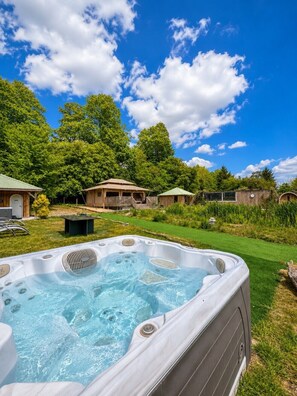 A hot tub in a backyard with a clear sky, surrounded by trees and a house. - 1 Bed in Thetford (oc-d33638) (Thompson)