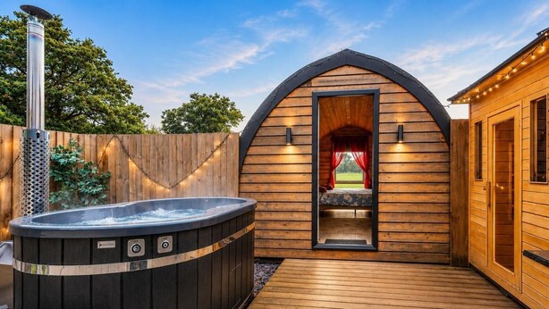 Eine Holzhütte mit Whirlpool, überdachtem Schlafbereich und einer Holzterrasse.