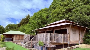 Ein rustikales Holzhäuschen mit Veranda, ein separates Gebäude mit Gründach und einem gepflegten Rasen.