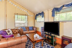 Ein gemütliches Wohnzimmer mit Ledersofa, Couchtisch, Flachbildfernseher und Kamin.