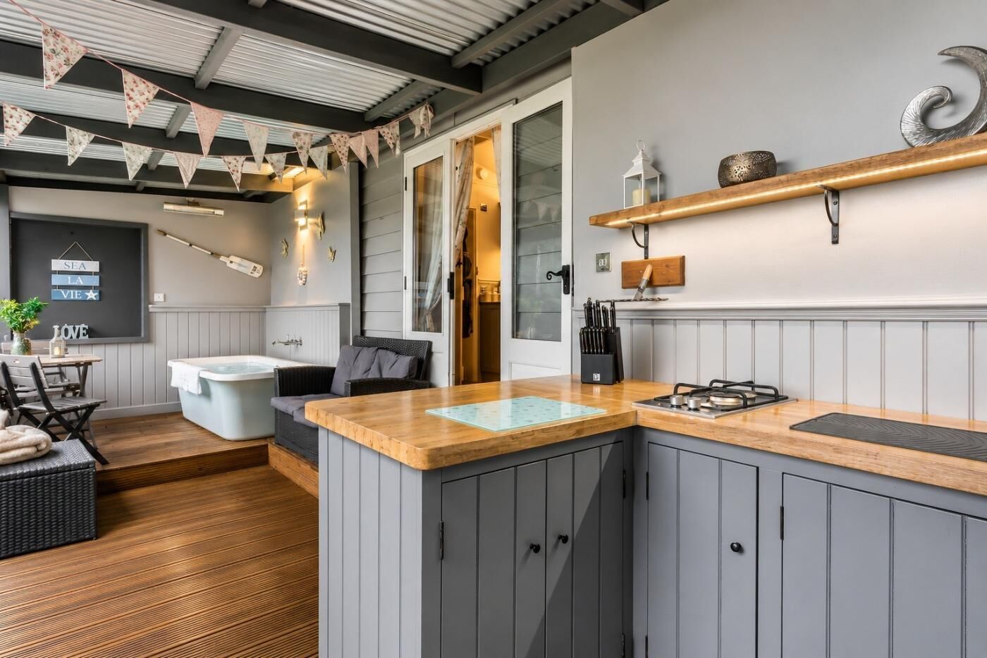 Une cuisine moderne avec des meubles gris, un plan de travail en bois et une cuisinière intégrée.