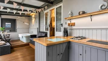 Une cuisine moderne avec des meubles gris, un plan de travail en bois et une cuisinière intégrée.