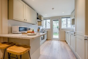 Eine Küche mit Mikrowelle, Toaster und Holzschemeln.