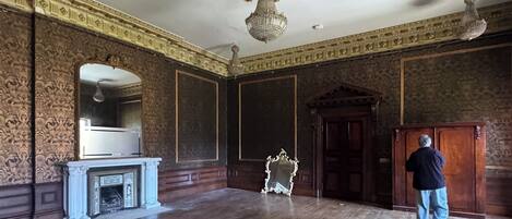 A spacious room with a large mirror, a fireplace, and a chandelier.