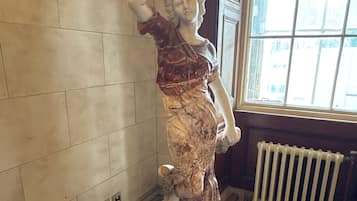 A statue in a room with tiled walls, a radiator, and a window.