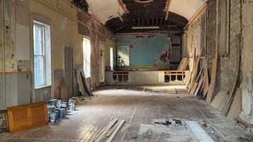 A large room with a high ceiling, exposed beams, and a partially renovated floor.