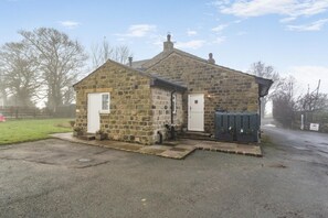 A stone building with a door and windows, a paved driveway, and a grassy area with a fence. - 1 Bed in Otley (oc-b34988) (Otley)