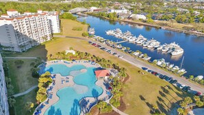 A resort with a large swimming pool, marina, and adjacent hotel buildings. - Dew Drop Inn Resort Villa with Massive Pool Oasis (North Myrtle Beach)