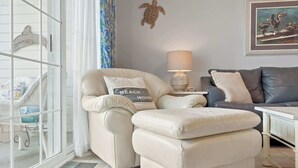 A living room with a sofa, ottoman, and a lamp. - Dew Drop Inn Resort Villa with Massive Pool Oasis (North Myrtle Beach)