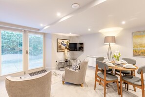 A modern living room with a dining area, large windows, and a flat-screen TV. - 2 Bed in Keswick (oc-d35022) (Keswick)