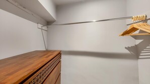 Une pièce avec une commode en bois, une tringle en métal pour suspendre les vêtements et un mur blanc.