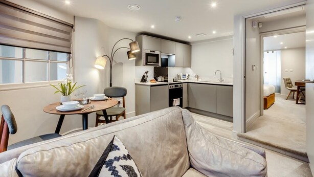 Un appartement moderne comprenant un coin repas, une cuisine et un salon avec un canapé et une petite table.