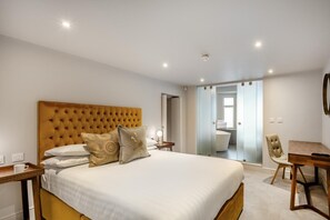 A hotel room with a large bed, a desk, and a bathroom visible through an open door. - 1 Bed in Keswick (oc-n35024) (Keswick)