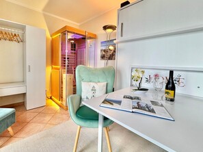 Ein modernes Zimmer mit einem grünen Sessel, einem Tisch mit einem Buch und einer Weinflasche sowie einer Wand mit einem dekorativen Gegenstand.